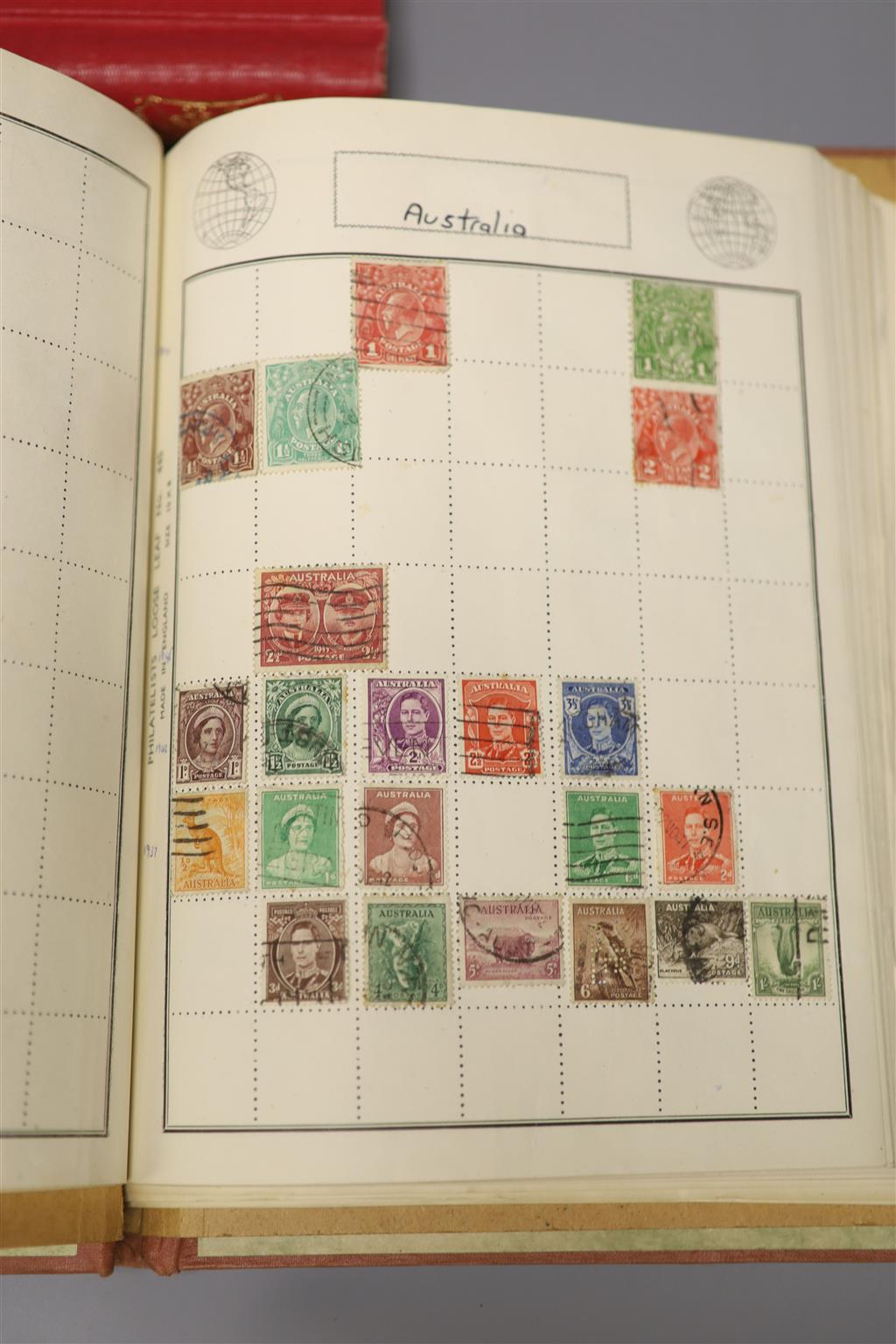 A Stanley Gibbons red stamp album and two others, each mounted with an accumulation of all world postage stamps